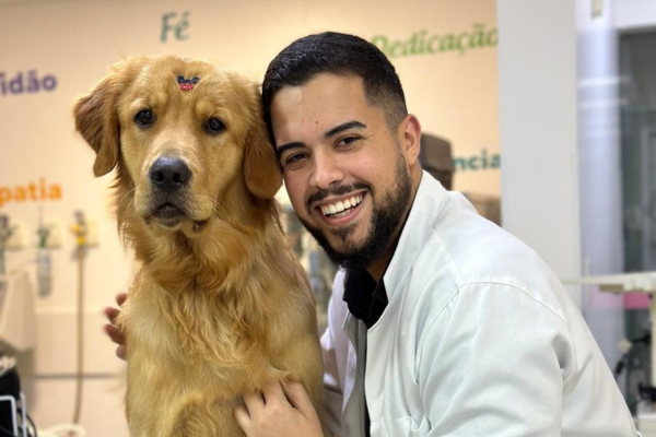 Veterinário do Inova Hospital Veterinário 24h sorrindo ao lado de um Golden Retriever durante atendimento clínico, demonstrando cuidado humanizado com o pet.