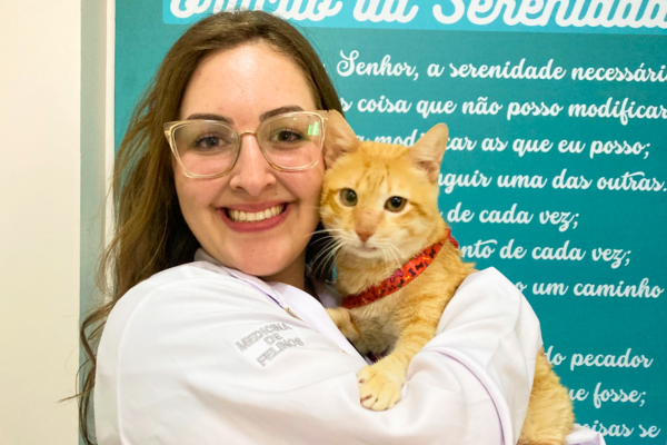 Veterinária da Inova 24h segura gato laranja no colo em ambiente clínico.