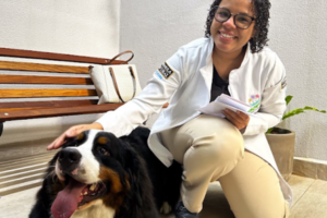 Médica-veterinária acaricia um cão da raça Bernese Mountain Dog durante atendimento em uma clínica veterinária, representando os cuidados preventivos com a saúde e o diagnóstico precoce de doenças como a giárdia.